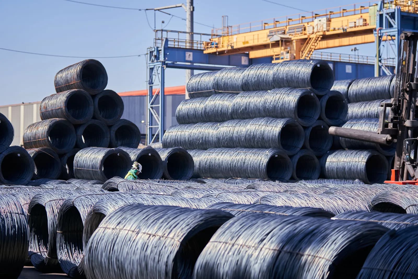 Stacked coils of steel wire rod in an industrial yard representing bulk construction materials