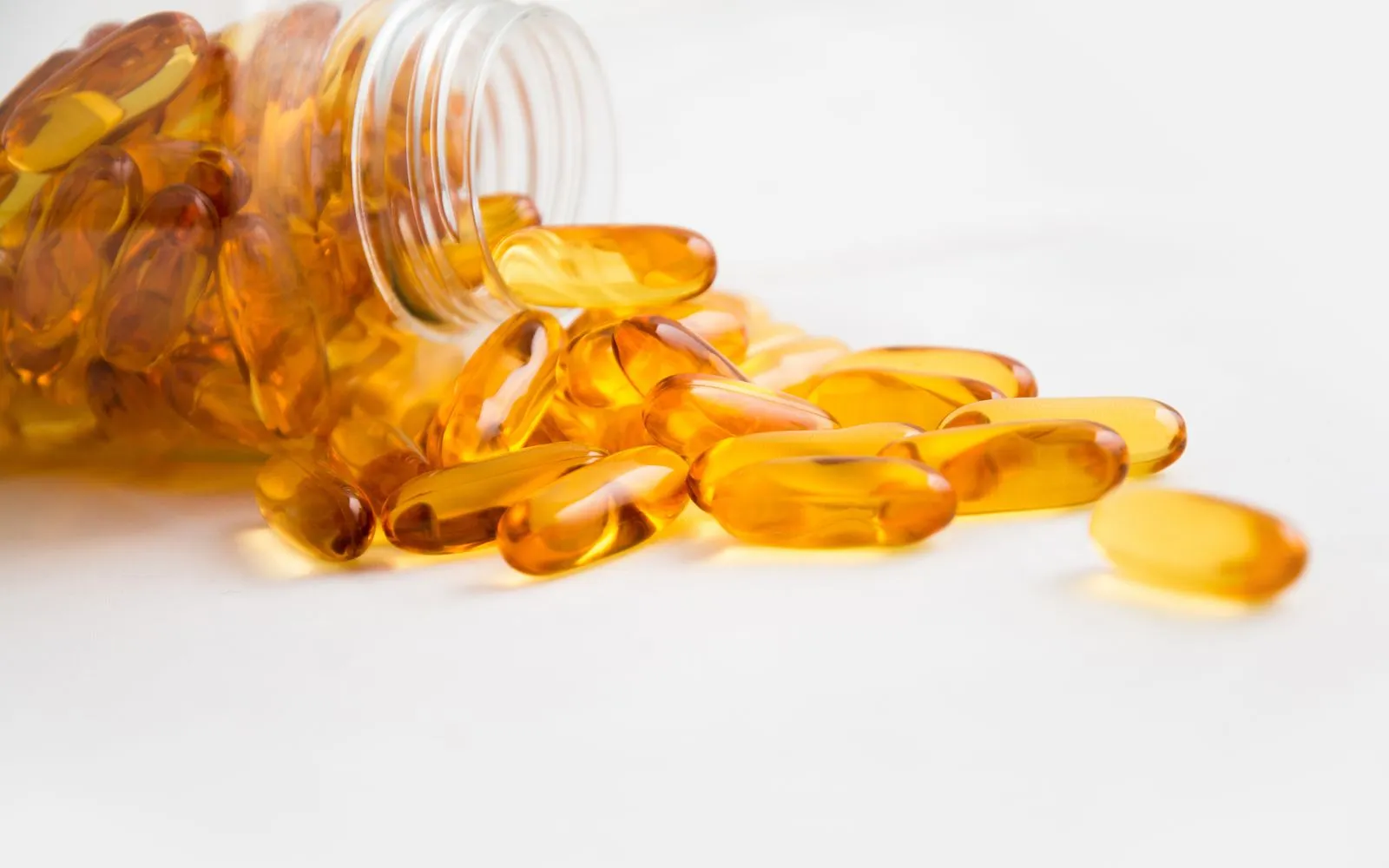 Amber softgel supplement capsules spilling from a bottle